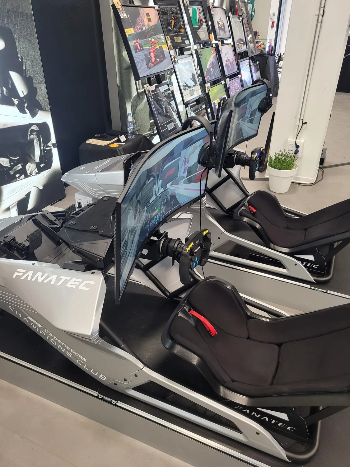 Simuladores Fanatec del F1 Champions Club en sala, con memorabilia enmarcada al fondo