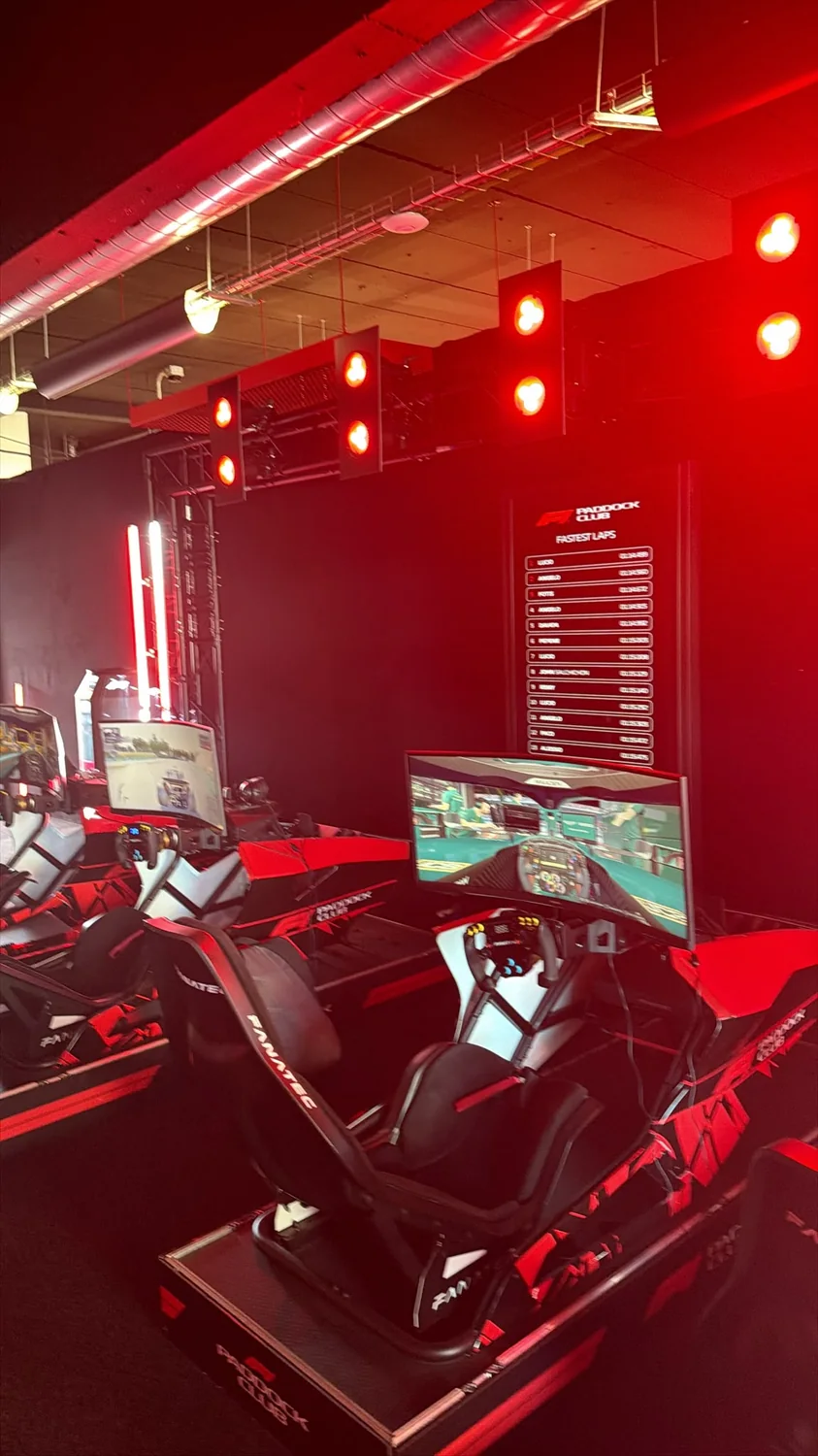 Sala de simuladores del F1 Paddock Club con iluminación roja y marcador de vueltas rápidas