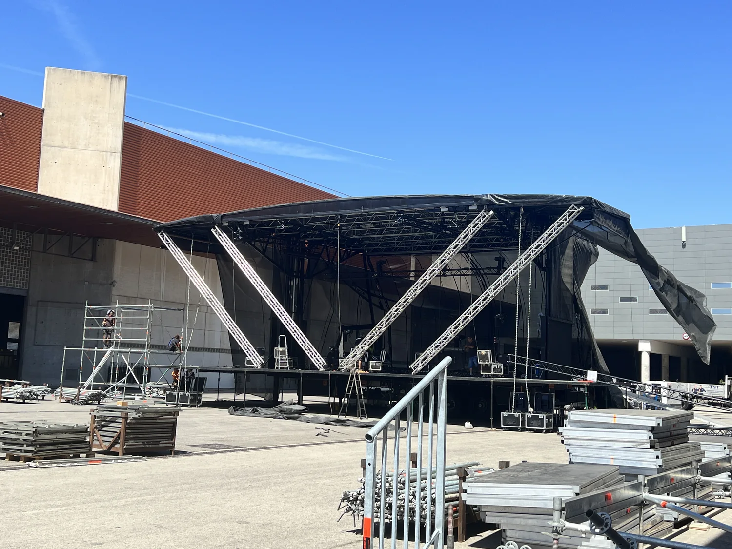 Cubierta del escenario montada con truss y lona, con material de montaje apilado en el recinto