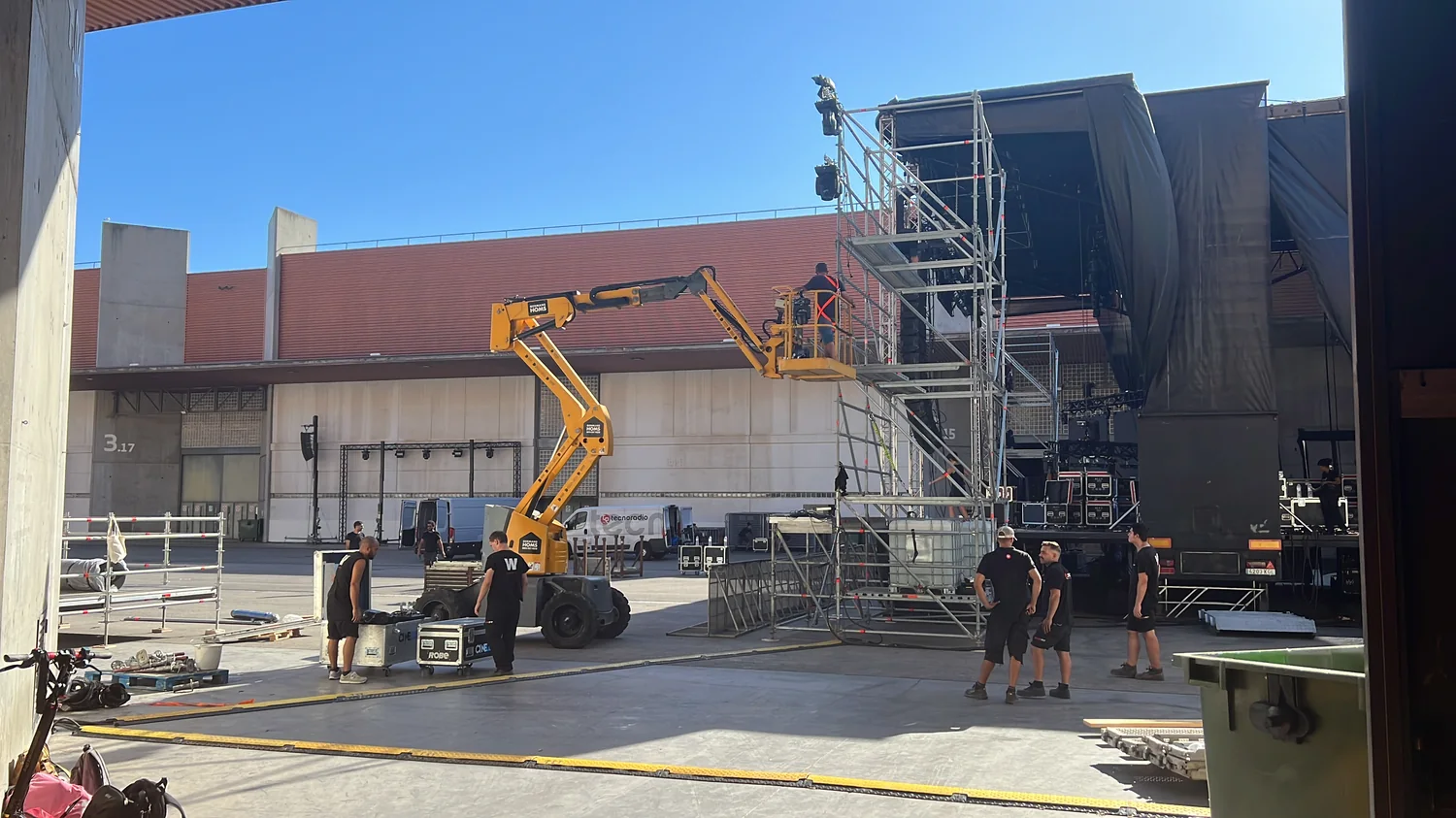 Montaje del escenario en exterior con plataforma elevadora, torres de estructura y equipos técnicos