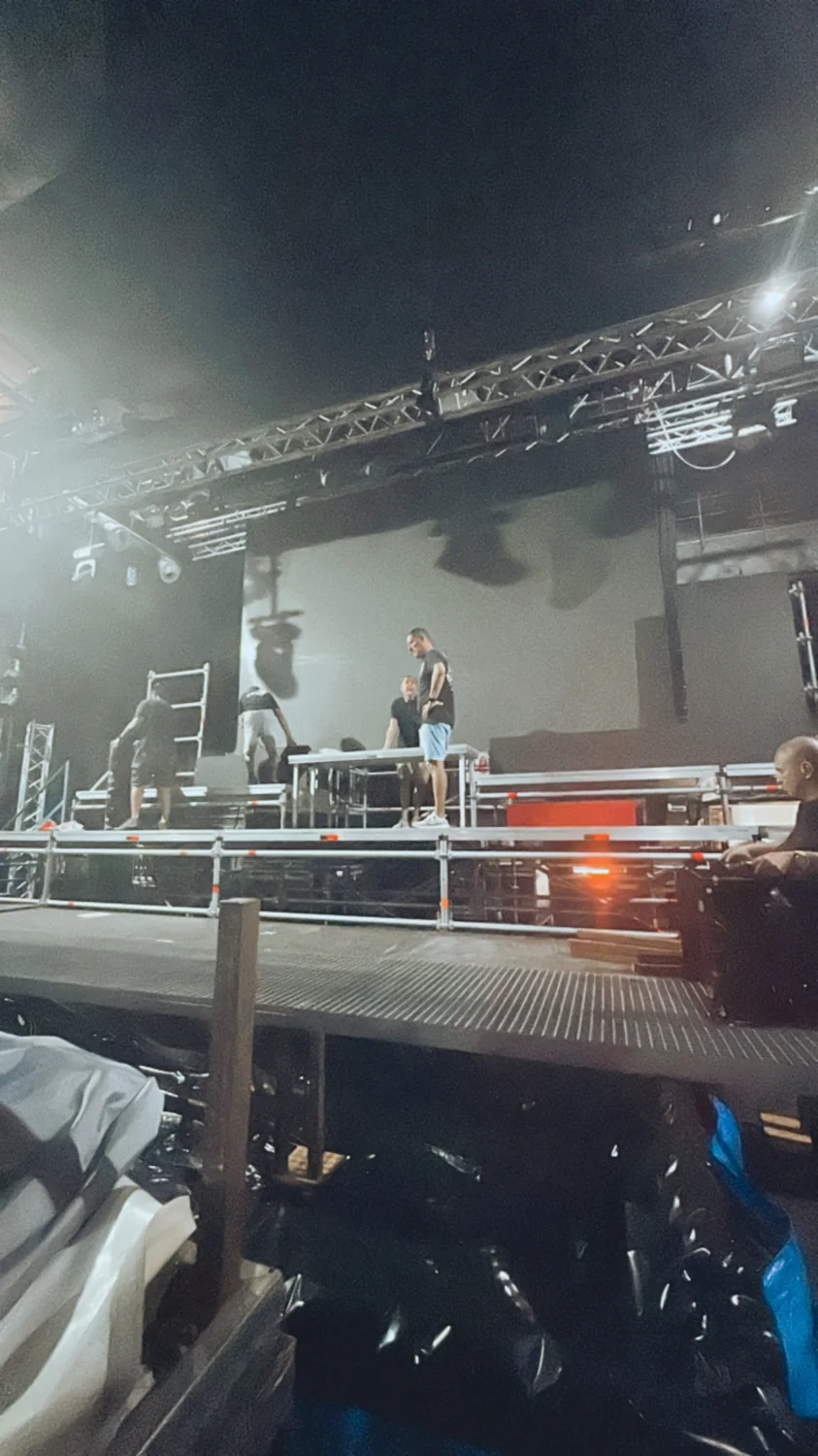 Montaje de escenario en sala, con truss colgado y equipo trabajando sobre plataforma