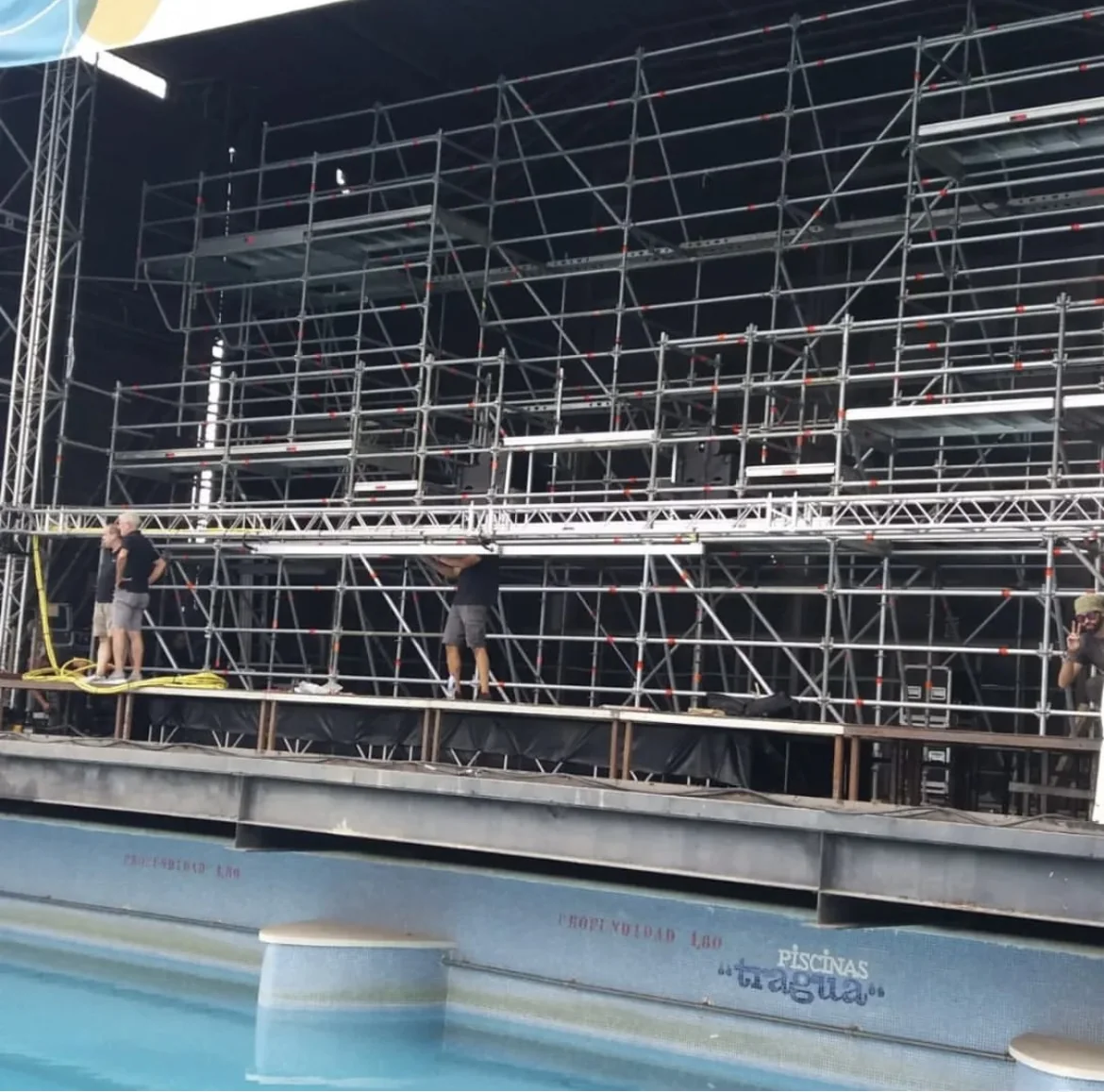 Montaje de escenario y grada de estructura junto a la piscina del recinto