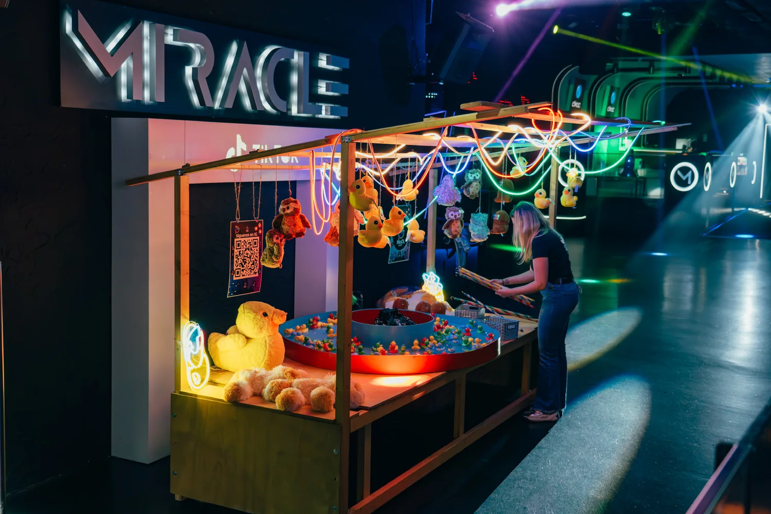 Puesto de juegos con neones y premios en una activación nocturna